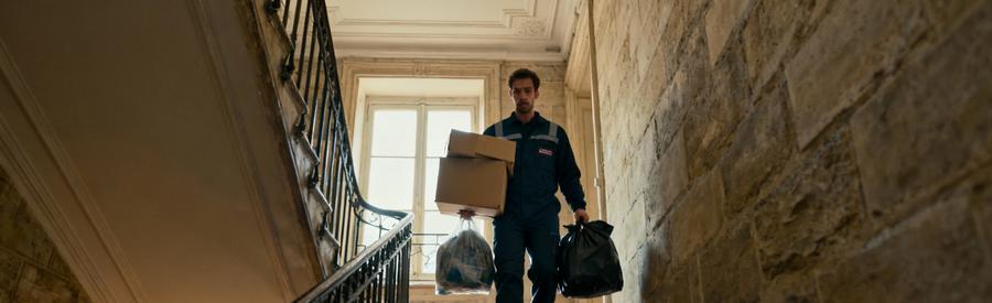 Professionnel évacuant encombrants dans escalier immeuble haussmannien typique du 11ème arrondissement parisien