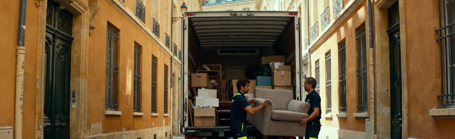 Camionnette de débarras dans rue étroite de la Presqu'île lyonnaise avec professionnels chargeant meubles