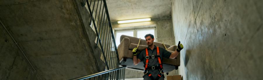 Professionnel Portage Escalier Immeuble Venissieux Débarrasseur avec harnais transportant canapé dans escalier d'immeuble collectif à Vénissieux