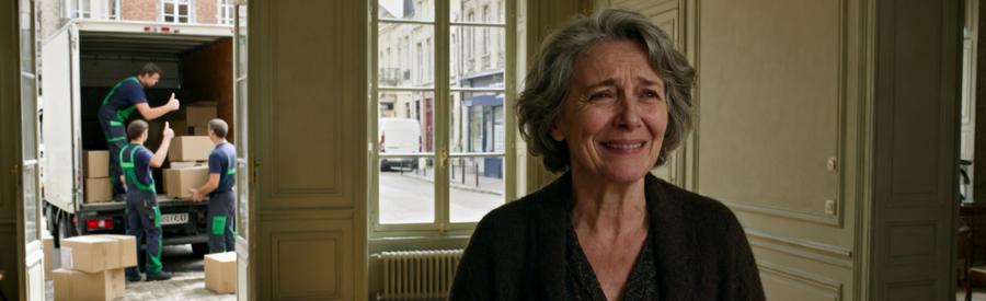 Femme satisfaite dans salon vide après débarras professionnel d'une maison en centre-ville du Pas-de-Calais. Équipe en action chargeant camionnette.