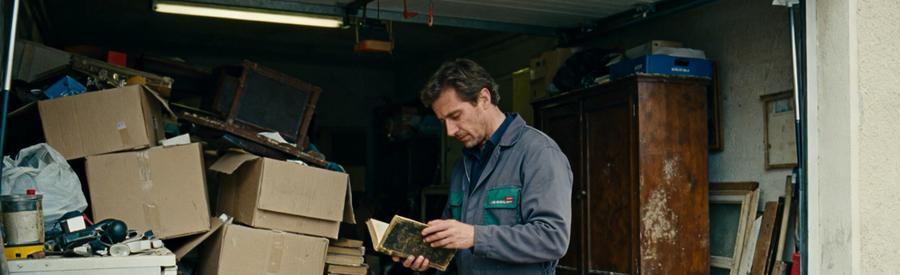 Professionnel du débarras évaluant un garage encombré dans une maison de Brunoy, avec divers objets accumulés.