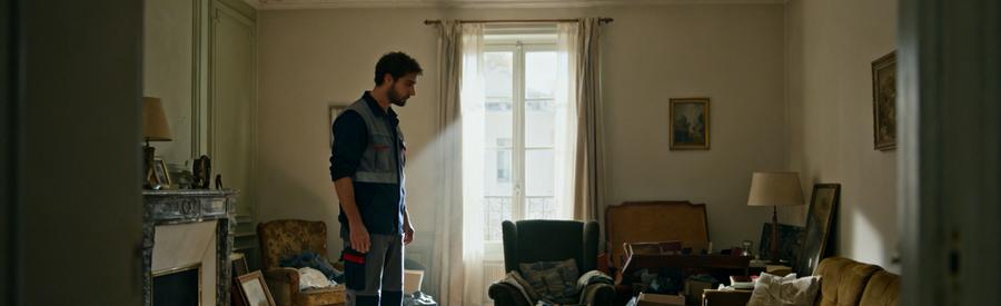 Un professionnel évalue un salon rempli de meubles et de cartons, représentant le débarras après un divorce.