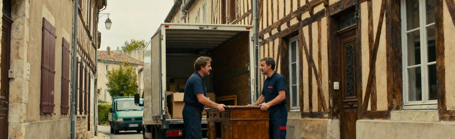 Des professionnels du débarras discutent dans une ruelle étroite à Mende, devant un camion de déménagement.
