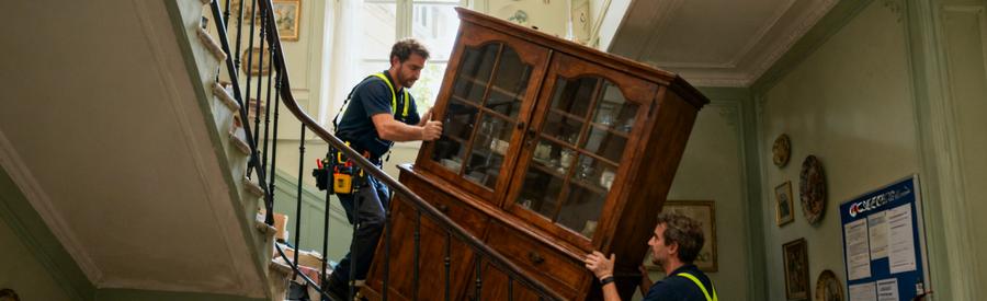 Professionnel du débarras descendant un buffet massif par des escaliers à Sèvres, mettant en évidence les défis du déménagement.