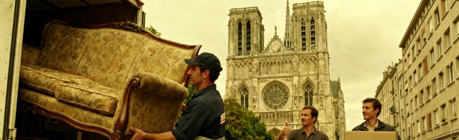 Débarras à Sens avec des professionnels transportant des meubles sur des rues pavées, cathédrale en arrière-plan.