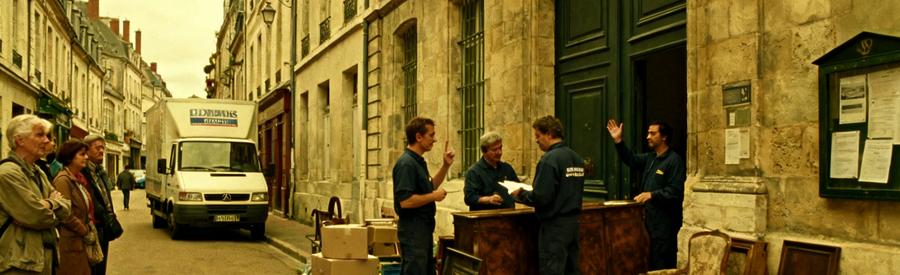 Professionnels du débarras évaluant des meubles anciens dans une rue piétonne à Tours, un défi logistique avec espaces étroits.