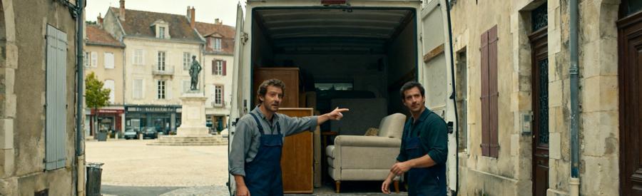 Professionnels du débarras à Bourgoin-Jallieu chargent une camionnette dans une rue étroite avec des bâtiments historiques.