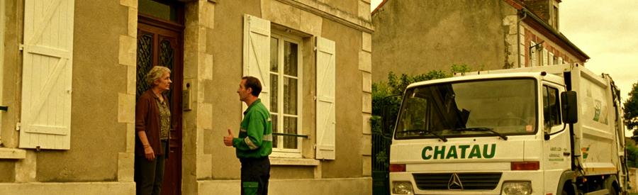 Un professionnel explique le service de débarras à un client devant une maison à Chatou, avec un camion à proximité.