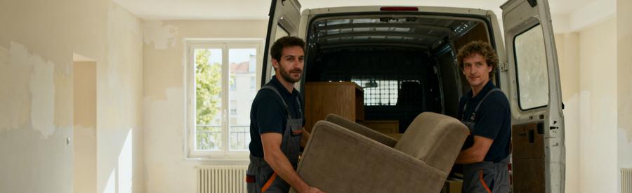 Professionnels du débarras à Massy chargent des meubles dans une camionnette, appartement en arrière-plan.