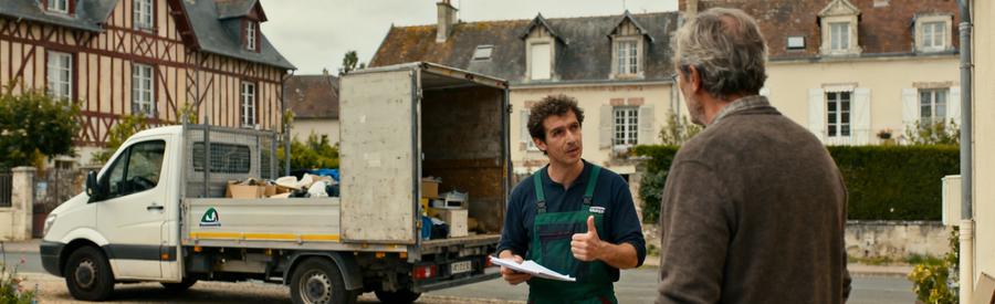 Un professionnel du débarras à Orléans évaluant des objets encombrants près d'une maison avec un camion en arrière-plan.