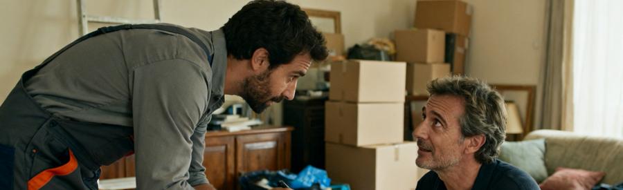 Un professionnel discute avec un client dans un salon semi-encombré, prêt à l'aider pour un débarras.