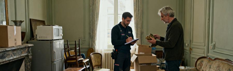 Un professionnel du débarras inspecte des meubles dans un salon au Mans, discutant avec un client sur le tri des objets.