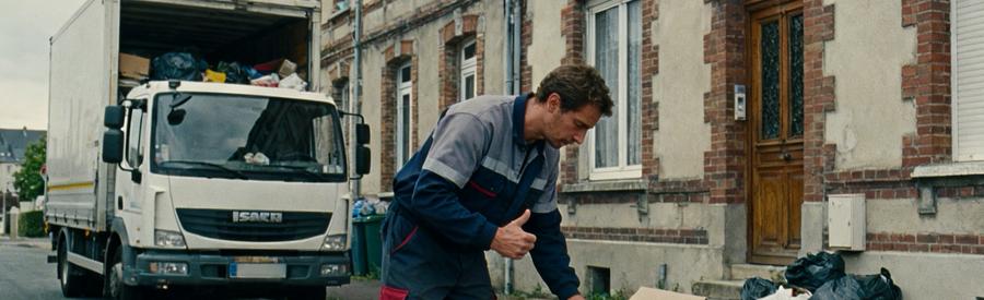 Professionnel du débarras inspectant des objets dans une maison ancienne à Calais, avec un camion en arrière-plan.