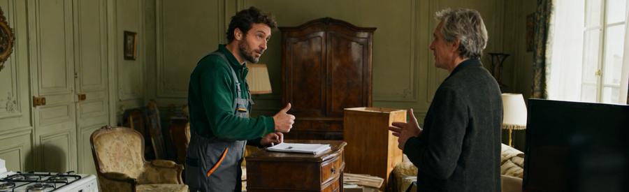 Professionnel du débarras en Mayenne inspecte des meubles anciens dans un salon, discutant de leur valeur.