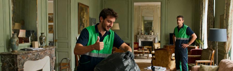 Deux débarras professionnels évaluent des objets dans un salon, illustrant leur expertise et collaboration.
