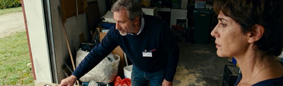 Un professionnel du débarras inspecte un garage, client observant les objets à trier pour réduire les coûts.