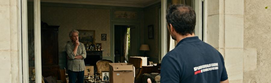 Un professionnel du débarras avec un membre de la famille dans une maison chargée d'objets personnels, symbole d'une succession.